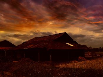 Abandoned house on field against sky during sunset