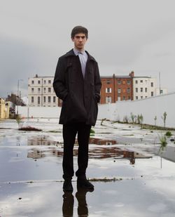 Portrait of young man standing in puddle