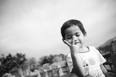 Boy showing peace sign against sky