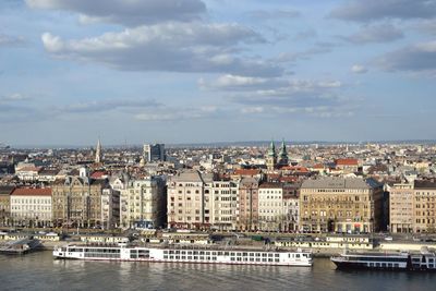 Sailboats in river by buildings in city against sky