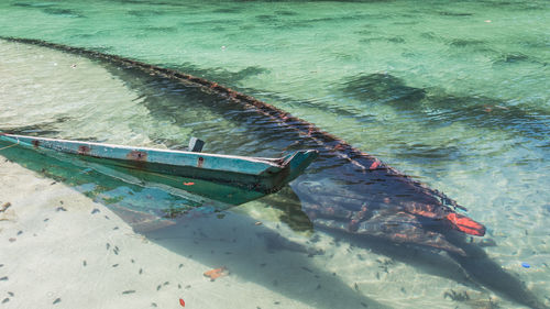 Broken longtail boat sunken in shallow water