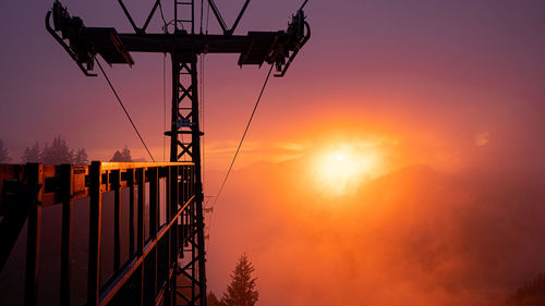 Silhouette cranes against sky during sunset