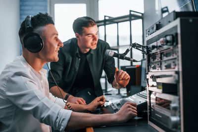 Conception of teamwork. two guys is indoors in the radio studio is busy by broadcast.