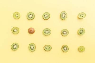 Slices and cuts of kiwi fruit on yellow background. healthy eating, travel or vacation concept