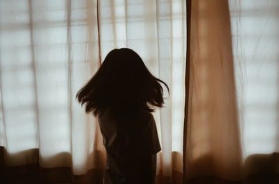 Woman looking away against window