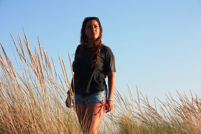 Young tanned woman in shorts at sunset time among the dry vegetation of sea sand dunes in tuscany