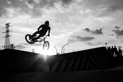 Low angle view of silhouette man jumping against sky