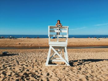 Teenage girl standing on lifeguard hut at beach