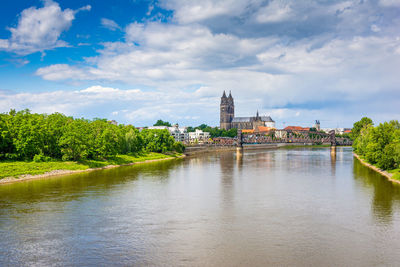 View of river amidst buildings against cloudy sky