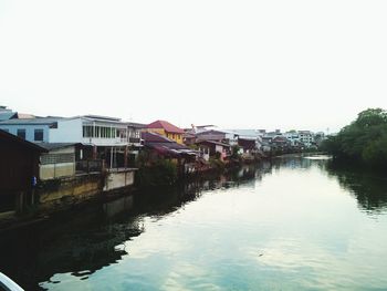 Houses by river against clear sky