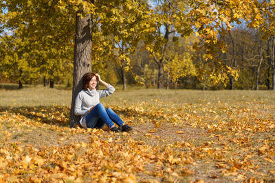 Full length of woman sitting on field during autumn