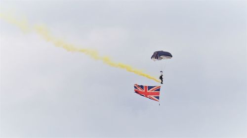 Low angle view of person paragliding with british flag against sky