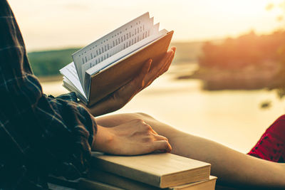 Rear view of man sitting on book against sky