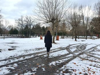 Rear view of girl walking on snow covered landscape