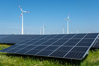 Solar panels on field against blue sky