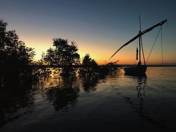 Silhouette trees by lake against sky during sunset