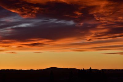 Silhouette landscape against dramatic sky during sunset