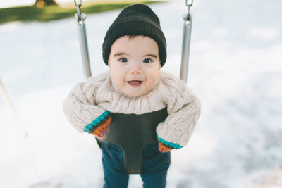 Portrait of cute baby boy swinging during winter