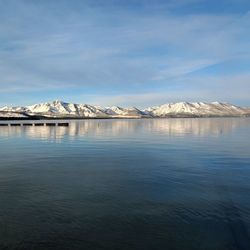 Scenic view of lake by snowcapped mountain against sky