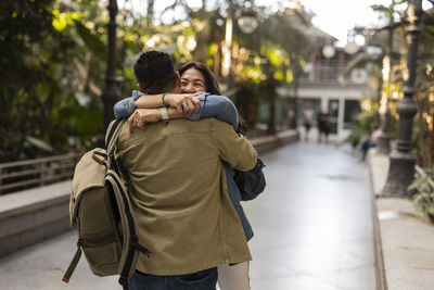 Happy woman embracing man on footpath in park