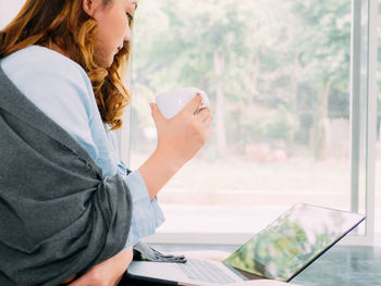 Midsection of young woman drinking coffee