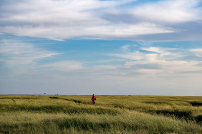 Rear view of woman on grassy field against sky