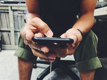 Midsection of man using mobile phone sitting at home