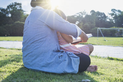 Rear view of woman sitting on field