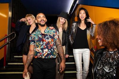 Group of stylish multiracial friends walking together on city street for party at night