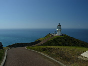 Lighthouse by sea against clear sky