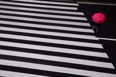 Low section of person walking on street with zebra crossing during monsoon