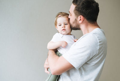 Happy father young man kissing baby girl little daughter at home