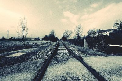 Railroad tracks amidst bare trees against sky