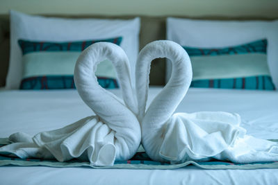 Close-up of white towels of heart shape on bed at hotel room