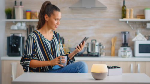 Young woman using mobile phone at table