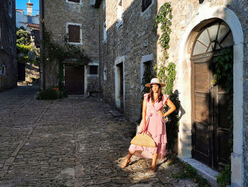 Young woman in pink dress in square of old town, stone buildings, fashion, lifestyle, travel.