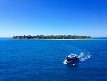 Boat sailing in sea against clear blue sky