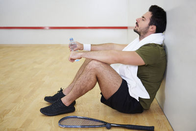 Side view of tired man sitting on floor at court