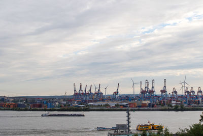 Cranes at commercial dock against sky