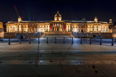 Illuminated building in city against sky at night