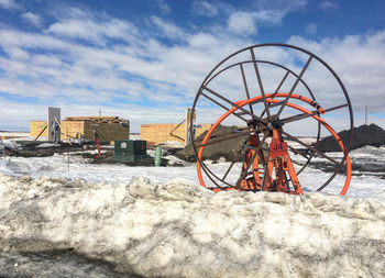 Ferris wheel on snow covered field against sky