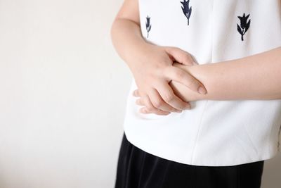 Midsection of woman standing against white background