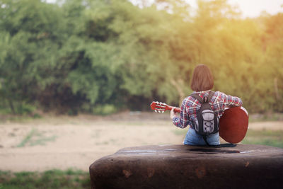 Boy playing with toy sitting on tree