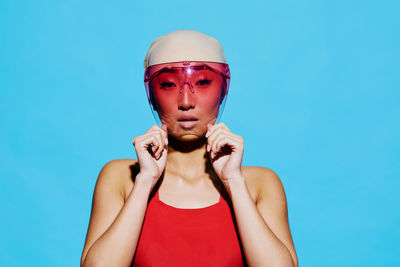 Portrait of young woman against blue background