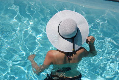 Rear view of young woman swimming in pool
