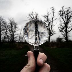 Close-up of hand holding glass against the sky