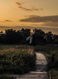 Scenic view of landscape with windmill against sky during sunset