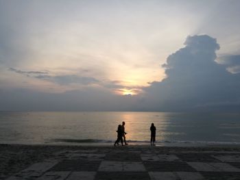 People on beach against sky during sunset