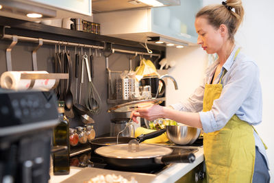 Side view of woman holding food in kitchen