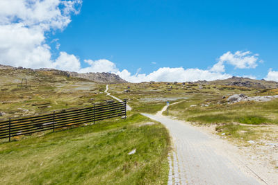 Road amidst field against sky